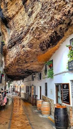 people are sitting in the middle of an alley way under a large rock formation that has been carved into it