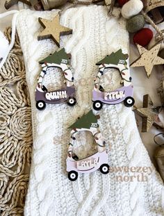 two christmas ornaments are laying on top of a white blanket and some other holiday decorations