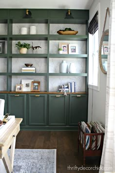 a living room filled with lots of green bookshelves