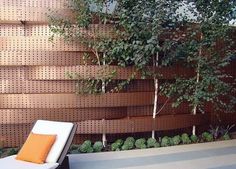 a white lounge chair sitting in front of a wall with trees growing on it's sides