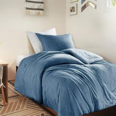 a blue comforter on a bed in a bedroom next to a night stand and lamp