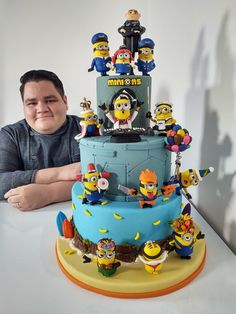 a man sitting in front of a cake with minion characters on it