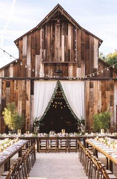 a barn with tables and chairs set up for an outdoor wedding