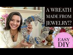 a woman is holding up a wreath made from pearls and other beadwork items