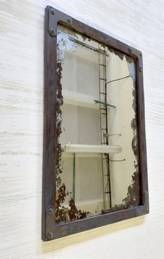 a mirror that is on the wall with some shelves in front of it and a ladder behind it