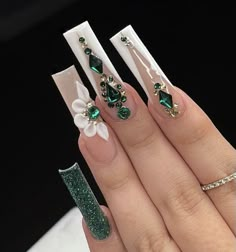 a woman's hand with green and white nail polishes on her nails, decorated with flowers