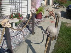 some fake human heads are tied up to poles on the side of a house in front of a flower pot