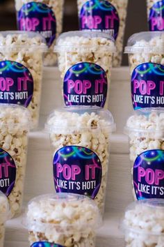 plastic cups filled with popcorn sitting on top of a table next to each other in front of the words pop it like it's hot