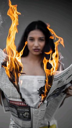 a woman holding a newspaper with flames coming out of it