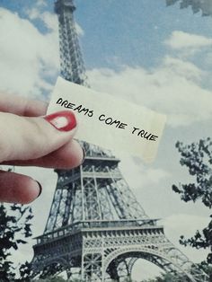 a person holding up a piece of paper with the eiffel tower in the background