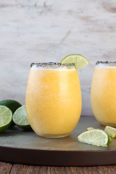 two glasses filled with orange juice and limes