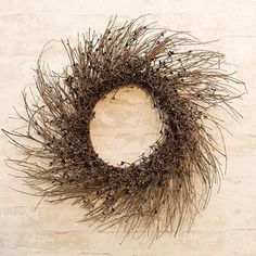 a dried twig wreath on a white brick wall with no one in the photo