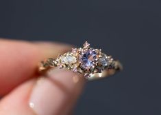 a person holding a ring with two different colored stones