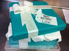 a birthday cake with a gift wrapped in blue and white paper