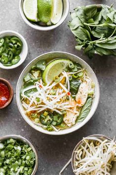 several bowls filled with different types of food and garnished with limes, cilantro, snap peas, and shredded cheese