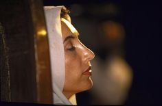 a woman with her eyes closed wearing a white headdress and looking off into the distance