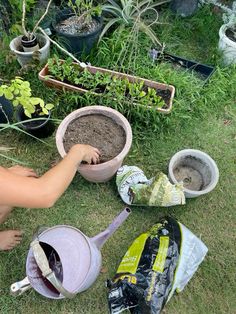 someone is digging in the ground next to some plants and pots with dirt on them