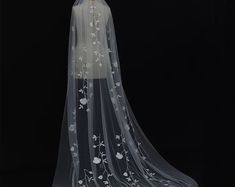 a wedding veil with white flowers on the bottom and long, thin veil at the top