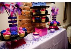 cupcakes and candles are displayed on a table in front of a brick wall