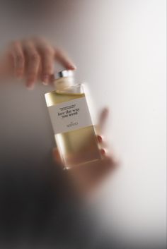 a person holding a bottle of perfume in their hand