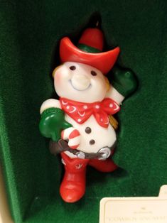 a small figurine in a green box with a red hat and scarf on