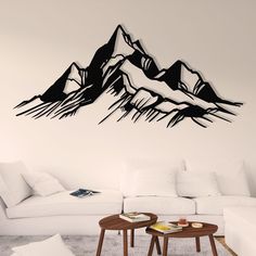 a living room filled with white furniture and a mountain wall decal on the wall