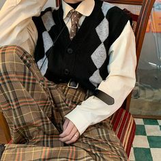 a man sitting on top of a chair wearing a sweater and tie