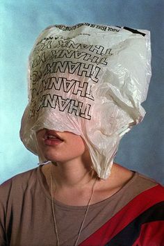 a woman wearing a plastic bag on her head with letters all over it's face