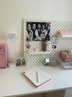 a white desk topped with a laptop computer next to a shelf filled with pictures and other items