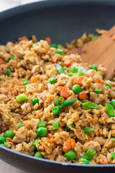 rice and peas are mixed together in a skillet with a wooden spoon on the side