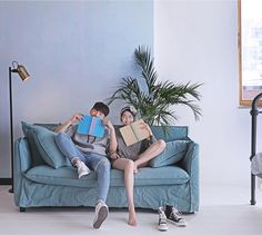 two people sitting on a couch holding books