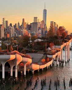 an aerial view of the city skyline at sunset with water and trees in foreground