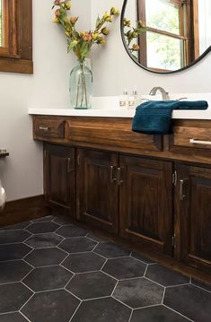 a bathroom with a sink, mirror and wooden cabinetry on the wall above it