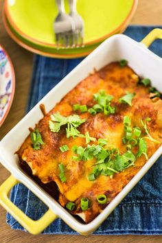 chicken enchiladas in a white casserole dish with cilantro and green onions