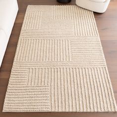 a white couch sitting on top of a wooden floor next to a rug covered in lines