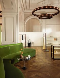 a living room filled with green couches next to a coffee table and chandelier