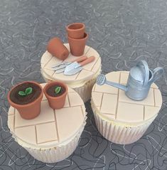 three cupcakes with gardening themed decorations on them