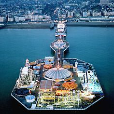 an aerial view of a pier with ferris wheel in the foreground and cityscape in the background