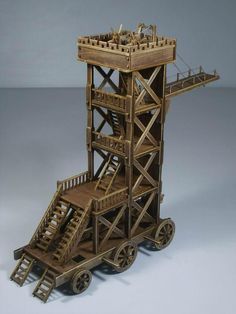 a wooden model of a tower with stairs and railings on wheels, made out of wood