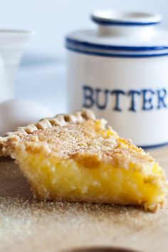 a piece of pie sitting on top of a wooden table next to a butter container