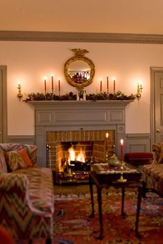 a living room filled with furniture and a fire place under a mirror on the wall