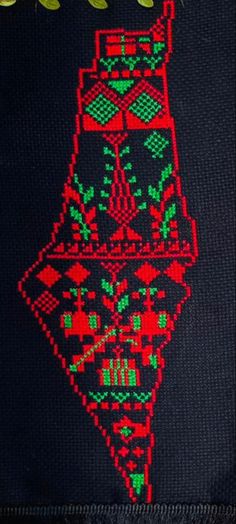 a close up of a cross stitch pattern on a piece of cloth with words written in green and red