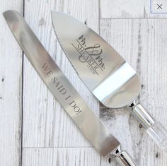 two personalized stainless steel cheese knives on a white wooden table with the words we said i do written on it