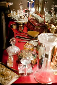 a red table topped with lots of glass vases and other items on top of it