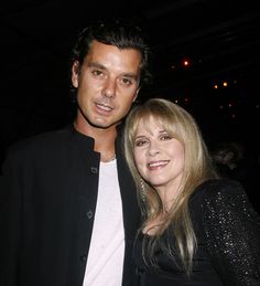 a man standing next to a woman in a black jacket and white t - shirt