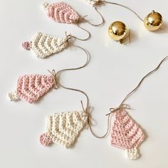 crocheted mittens and bells are arranged on a white surface with gold ornaments