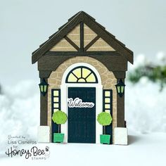 a small house made out of paper with a welcome sign on it's front door