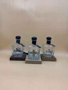 three glass bottles sitting on top of wooden bases