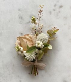 a boutonniere with flowers and greenery on a marble surface