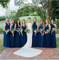 a group of women standing next to each other on top of a rug in front of a tree